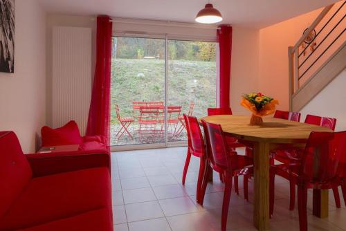 a dining room with a wooden table and red chairs at Gîtes de l'Orée du Bois - Boussières in Boussières