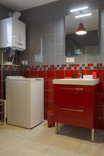 a red and white kitchen with a sink and a mirror at Gîtes de l'Orée du Bois - Boussières in Boussières