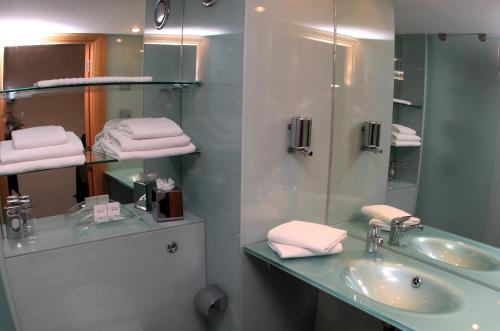 een badkamer met een wastafel, een spiegel en handdoeken bij Station House Hotel Letterkenny in Letterkenny