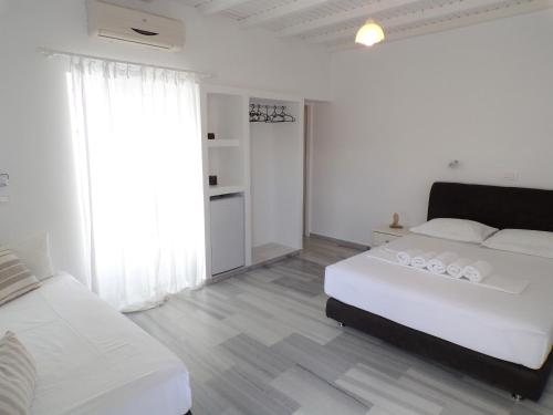 a white bedroom with a bed and a large window at Villa Irini in Naousa