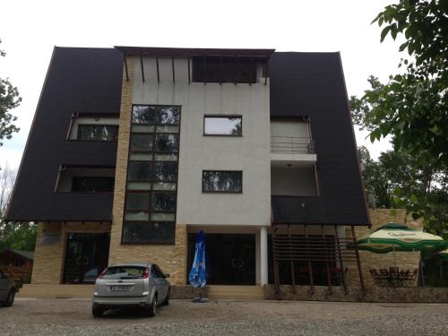 a building with a car parked in front of it at Pensiunea Carpe Diem in Râmnicu Vâlcea