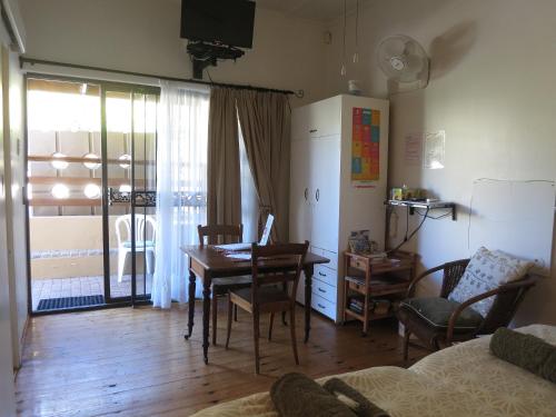 a living room with a dining room table and a desk at Dempsey's Self-Catering Guest House in Port Elizabeth
