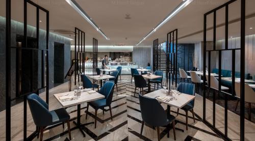 a restaurant with white tables and blue chairs at M Hotel Saigon in Ho Chi Minh City