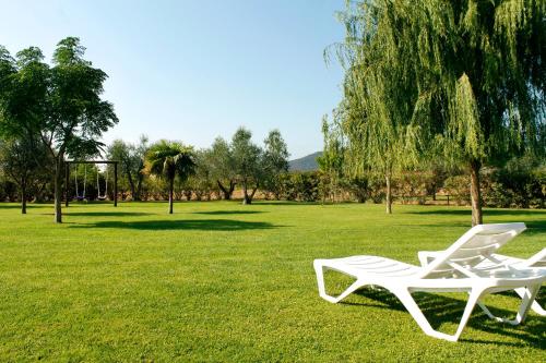 two white chairs sitting in the grass in a park at Agriturismo Bocci in Castiglione della Pescaia
