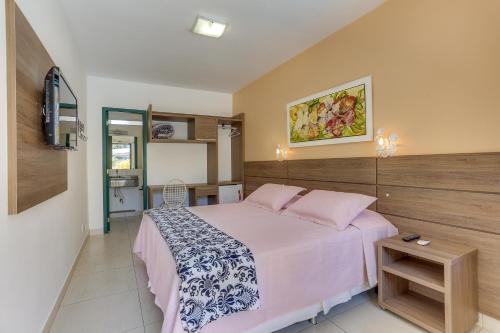 um quarto com uma cama grande e lençóis cor-de-rosa em Pousada Abaeté em Florianópolis