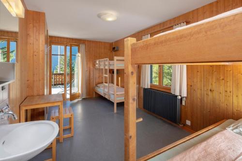 Grindelwald Youth Hostel في جريندلفالد: حمام مع سرير بطابقين ومغسلة في الغرفة