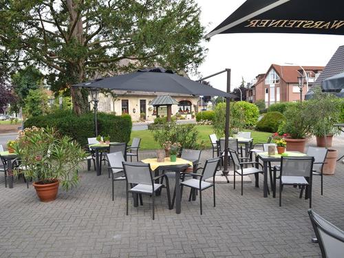 a patio with tables and chairs and an umbrella at Hotel Gasthof Kruse in Nottuln