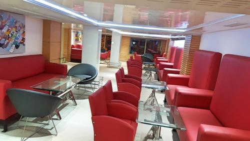 a waiting room with red chairs and tables at Hotel VELSATIS in Beni Mellal