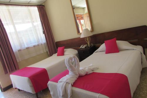 Una habitación de hotel con 2 camas y una toalla. en Hotel La Siesta en Liberia