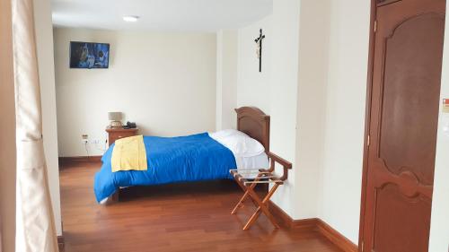 a bedroom with a bed with blue sheets and a chair at Hotel Casa de Peregrinos in Ipiales