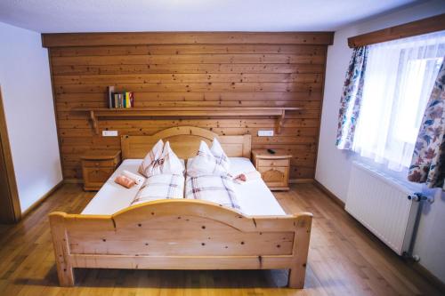 a bedroom with a bed with a wooden wall at Prünsterhof in Obertilliach