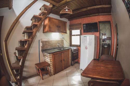 a small kitchen with a spiral staircase in a house at Pousada Pé na Areia in Garopaba