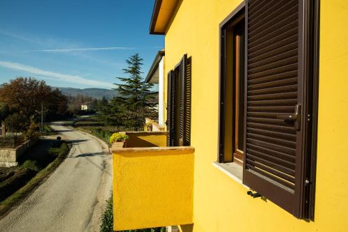 a yellow building with an open window and a road at Appartamento Della Pia in Bevagna