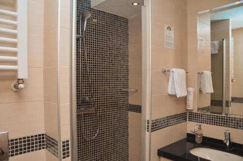 a bathroom with a shower with a sink and a mirror at Apartman Mitra Angella Konaci in Kopaonik