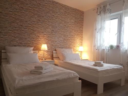 two beds in a bedroom with a brick wall at Appartement "Orchidee" in Hoya