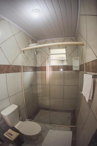 a small bathroom with a toilet and a shower at Pousada Pé na Areia in Garopaba