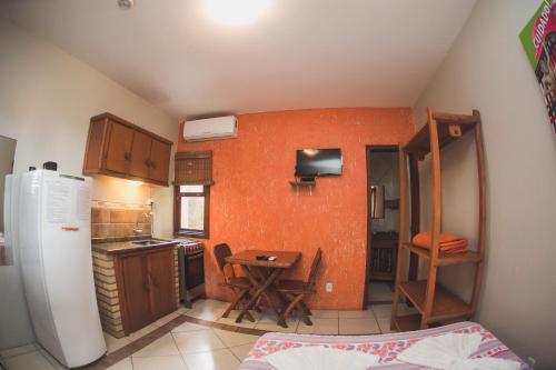 a small kitchen with a table and a refrigerator at Pousada Pé na Areia in Garopaba