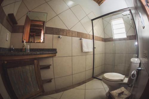 a bathroom with a toilet and a sink and a mirror at Pousada Pé na Areia in Garopaba