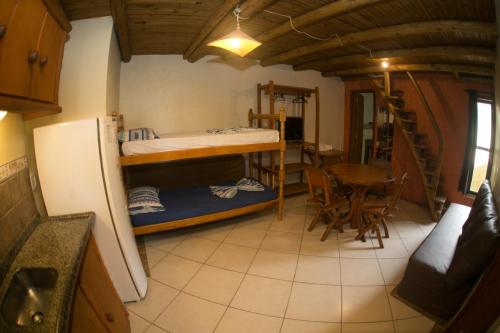 a small room with a bunk bed and a table at Pousada Pé na Areia in Garopaba