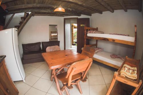 a room with a table and a couch and bunk beds at Pousada Pé na Areia in Garopaba