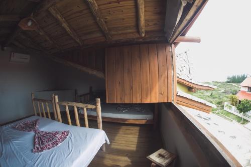 a small room with a bed and a wooden floor at Pousada Pé na Areia in Garopaba