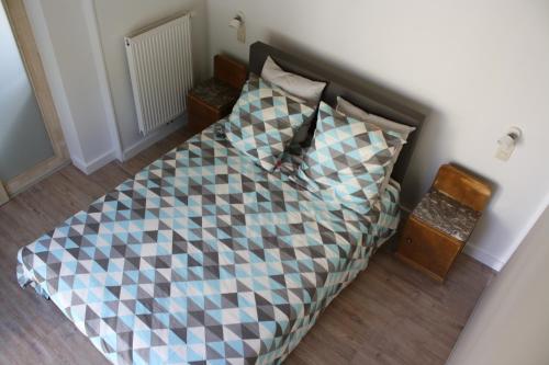 a bed with a checkered blanket and two pillows at Vakantiehuis Schardauw in Damme
