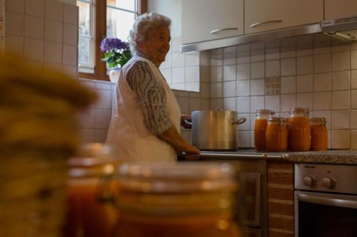 an older woman standing in a kitchen preparing food at Pension der Steinbock - das 300 Jahre alte Bauernhaus - TIROL in Sankt Anton am Arlberg