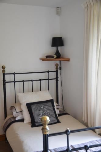 a bed with a black frame and a pillow on it at Woodland Guesthouse in Stow on the Wold