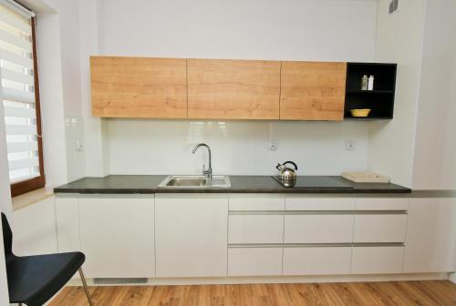 a kitchen with white cabinets and a sink at Poduszka Apartamenty Zdrojowe in Nałęczów