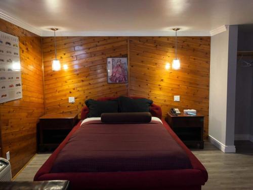 a bedroom with a large bed and wooden walls at Motor Court Motel in London