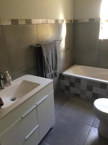 a bathroom with a sink and a tub and a toilet at 20A Castleton in Plettenberg Bay