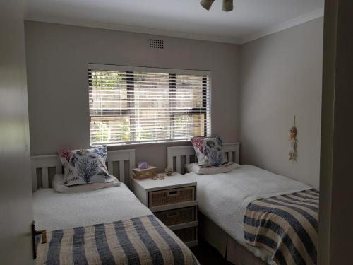a bedroom with two twin beds and a window at 20A Castleton in Plettenberg Bay