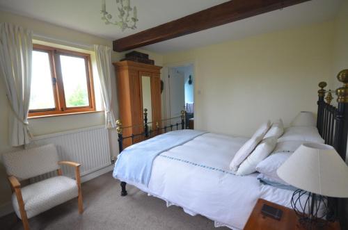 a bedroom with a bed and a chair and a window at Woodland Guesthouse in Stow on the Wold