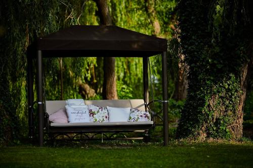 a bench in a gazebo in the grass at Hotel Lajta Park in Mosonmagyaróvár