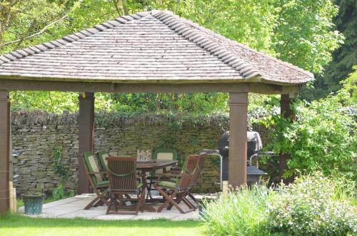 a wooden gazebo with chairs and a table at Woodland Guesthouse in Stow on the Wold