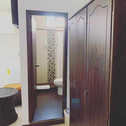 a bathroom with a toilet and a shower with wooden cabinets at Hostal Costa del Pacifico in Puerto Ayora