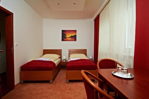 a room with two beds and a table and a dining room at Penzión Donet in Bratislava