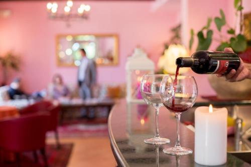 a person is pouring wine into two wine glasses at Country Hotel & Resort I Calanchi in Ripatransone