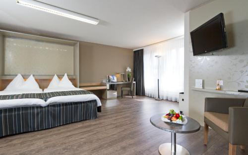 a hotel room with a bed and a table with a bowl of fruit at Hotel Olten Swiss Quality in Olten