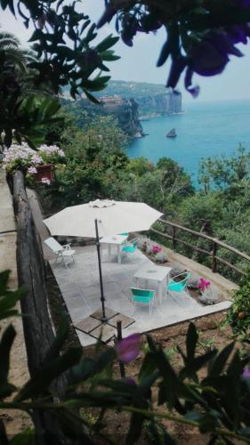 a patio with an umbrella and chairs and the ocean at La Palombara B&B in Vico Equense