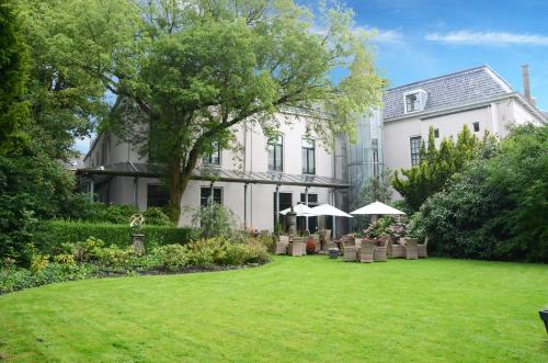 a white house with a lawn in front of it at Fletcher Hotel Paleis Stadhouderlijk Hof in Leeuwarden