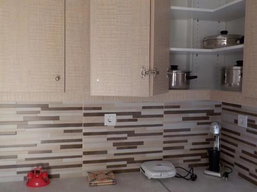 a kitchen with brown and white tiles on the wall at *OI.KO HOUSE* City Apartments in Kato Achaia