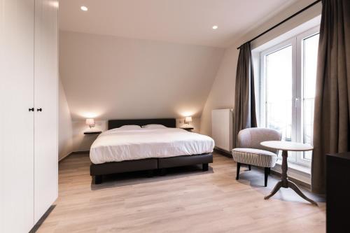 a bedroom with a bed and a table and a window at Duins Genot 5 star Holiday Homes 30p & 40p - Indoorpool & Wellness in Jabbeke