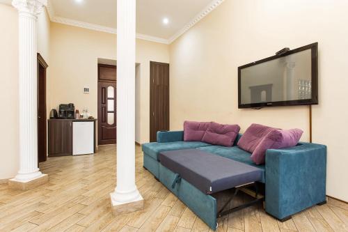 a living room with a blue couch and a flat screen tv at Hotel Baron in Odesa