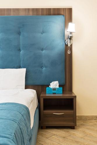 a bed with a blue headboard next to a nightstand with a blue bed at Hotel Baron in Odesa