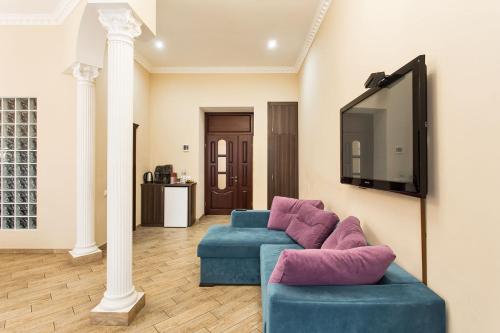 a living room with two blue couches and a tv at Hotel Baron in Odesa
