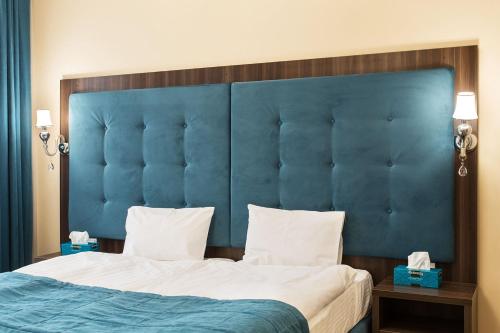 a bed with a blue headboard in a hotel room at Hotel Baron in Odesa