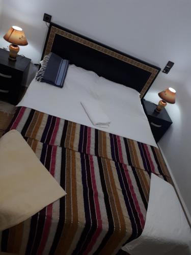 Un dormitorio con una cama con sábanas blancas y dos lámparas. en Mirleft Point, en Mirleft