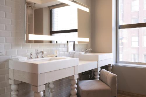 a bathroom with two sinks and a mirror and a chair at Virgin Hotels Chicago in Chicago