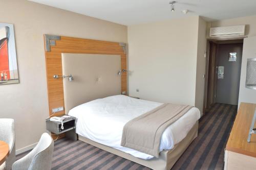 a hotel room with a bed and a table and chair at Côte Ouest Thalasso & Spa Les Sables d'Olonne - MGallery Collection in Les Sables-dʼOlonne